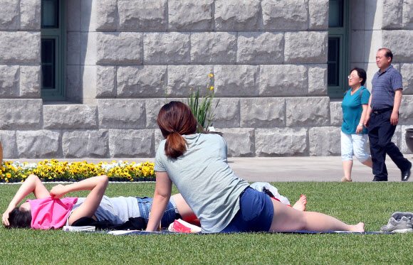 서울의 기온이 30도까지 올라간 23일 오후 서울광장에서 시민이 일광욕을 즐기고 있다.  연합뉴스