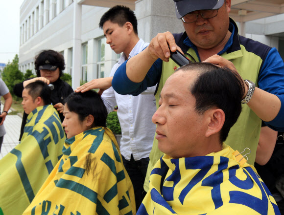 경남도가 폐업 결정을 발표한 지 사흘째인 31일 오후 진주의료원 본관 앞에서 지역 의료원 지부장들이 삭발을 하고 있다. 왼쪽부터 서산의료원 이창구 지부장, 홍성의료원 진락희 지부장, 부산의료원 이충희 지부장. 연합뉴스