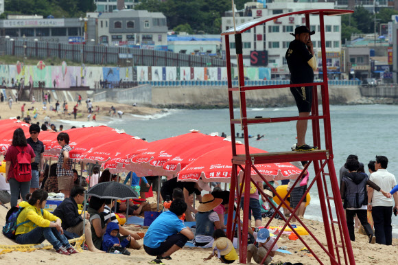 2일 부산 해운대해수욕장에서 피서객들이 더위를 식히고 있는 가운데 해경과 119수상구조대가 망루 근무를 하고 있다. 부산에서는 해운대, 광안리, 송도, 송정해수욕장이 1일 조기 개장했다. 연합뉴스