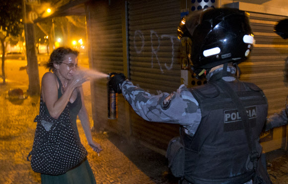 17일(현지시간)브라질의 수도 리우데자네이루 시위에 참여한 한 시민이 전투경찰이 쏜 최루가스를 얼굴에 맞고 고통스런 표정을 짓고 있다. 20년만의 최대 규모인 20만명의 시민이 참가한 이번 시위는 브라질의 낙후된 공공서비스와 경찰 폭력, 정치권의 부패에 대한 항의로 이뤄졌다. AP/IVARY