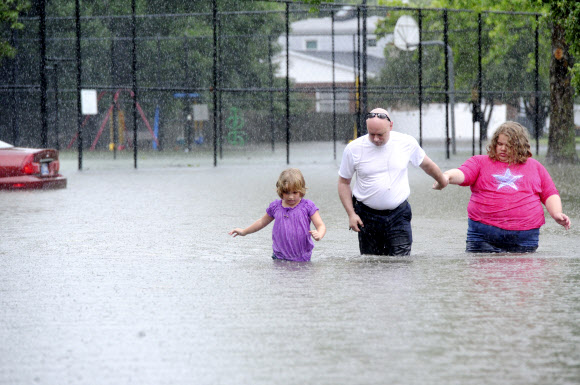 지난 24일 미국 인디애나주 에번즈빌에 홍수가 나 도로와 집이 물에 잠기자 한 남성이 두 딸과 함께 피신하고 있다. 에번즈빌 AP 연합뉴스   