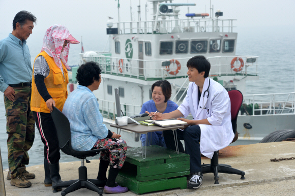 선착장에 정박 중인 인천 531호 앞에 차려진 임시 진료소에서 의료진이 섬주민들과 대화를 나누며 아픈 곳을 확인하고 있다.