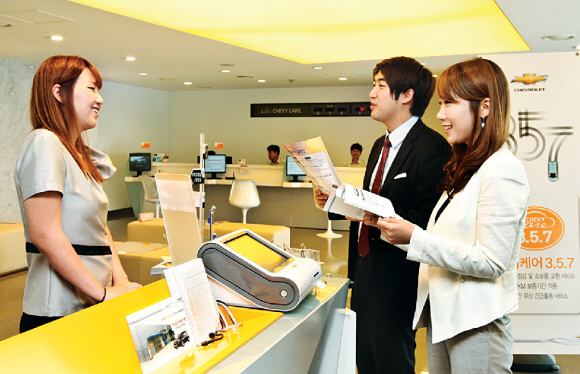 한국GM의 고객서비스센터에서 한 상담원(왼쪽)이 남녀 고객에게 ‘쉐비 케어’ 서비스에 대해 설명하고 있다. 한국GM 제공 