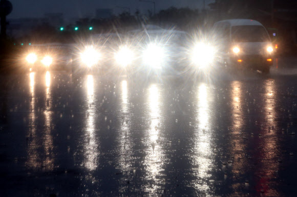 낮이야 밤이야 서울을 비롯한 중부지방에 많은 양의 비가 내린 22일 오전 서울 여의도 도로에서 차량들이 전조등을 켜고 운행하고 있다.  연합뉴스