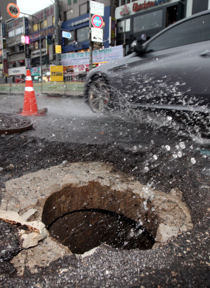 폭우가 내린 22일 오전 서울 사당역 인근 도로의 맨홀이 파손돼 교통이 통제되고 있다. 기상청은 이날 오전 7시10분을 기해 서울·경기·강원 지역에 호우경보를 발령했다. 연합뉴스