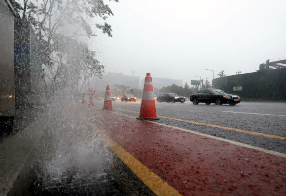 서울을 비롯한 중부지방에 많은 양의 비가 내린 22일 오전 서울 여의도 IFC몰 인근 도로의 배수구에서 빗물이 역류하고 있다. 연합뉴스