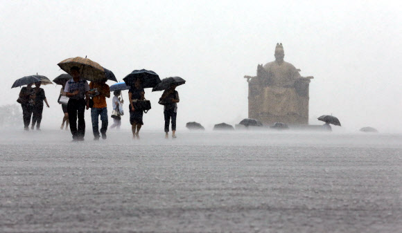 주말동안 잠시 소강상태를 보였던 장맛비가 다시 시작된 22일 오전 서울 광화문 광장을 지나는 출근길 시민들이 발걸음을 재촉하고 있다.  연합뉴스