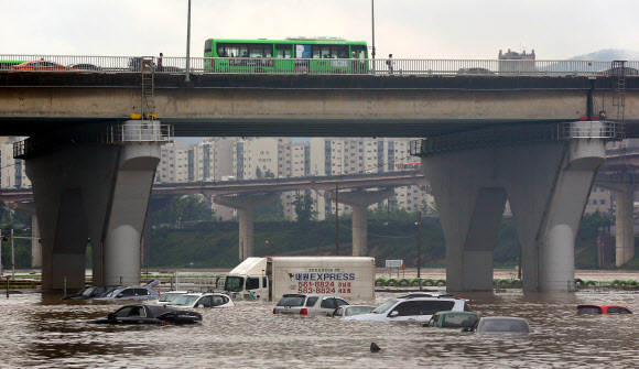 새벽부터 집중호우가 내린 22일 오전 탄천의 물줄기가 불어나 서울 탄천주차장에 주차된 차량이 물에 잠겨 있다. 연합뉴스