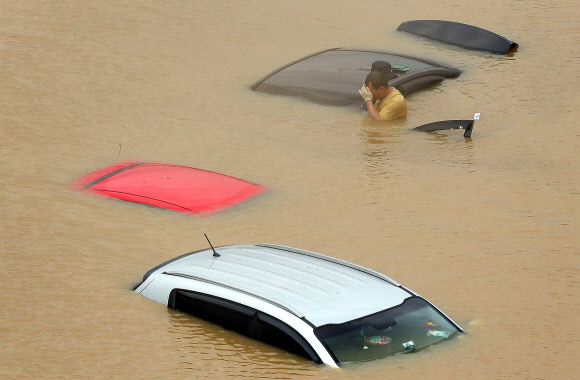 새벽부터 내린 집중호우로 침수피해를 입은 서울 탄천주차장에서 22일 오후 한 시민이 힘겨워하고 있다 연합뉴스