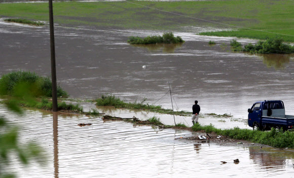 강원 영서남부를 중심으로 많은 비가 내린 22일 오전 원주시 부론면의 한 마을길이 인근 하천의 범람으로 침수돼 한 주민이 차에서 내려 도로를 바라보고 있다. 연합뉴스