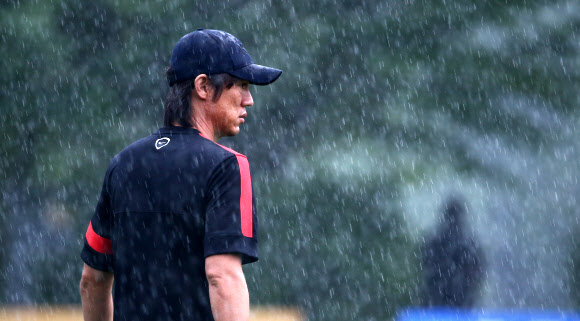 2013 동아시아연맹(EAFF) 축구선수권대회(동아시안컵) 중국과의 경기를 이틀 앞둔 22일 오후 경기도 파주 대표팀트레이닝센터(NFC)에서 홍명보 국가대표팀 감독이 비를 맞으며 잠시 생각에 잠겨 있다. <연합뉴스>