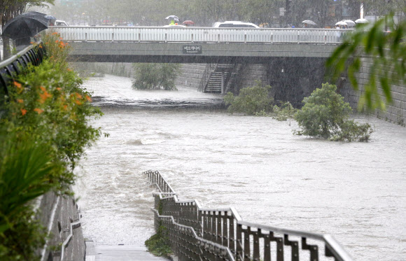 장마전선의 영향으로 비가 내린 23일 서울 청계천 인도가 물에 잠겨 있다. 연합뉴스