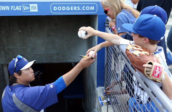 26일 오후(현지시간) LA다저스 스타디움에서 열린 다저스와 신시내티 레즈와의 경기를 앞두고 류현진이 어린이 관중들에게 사인볼을 건네주고 있다. 연합뉴스
