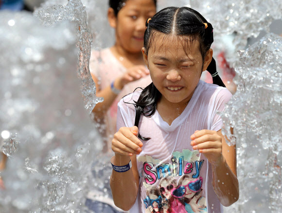 서울의 최고기온이 32도를 기록한 1일 오후 서울 광화문광장에서 한 아이가 물놀이를 하고 있다. 연합뉴스