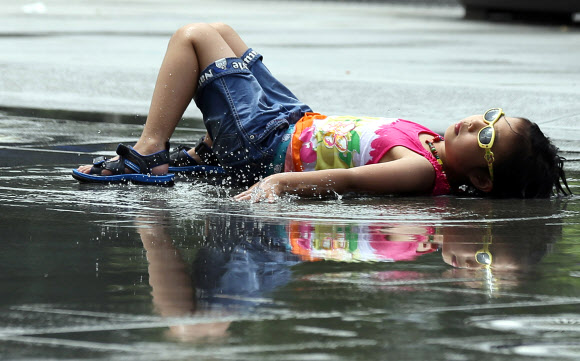 서울의 최고기온이 32도를 기록한 1일 오후 서울 광화문광장에서 한 아이가 물놀이를 하다 잠시 휴식을 하고 있다.  연합뉴스