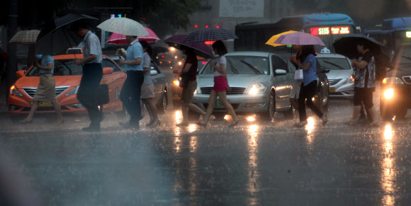 6일 오후 국지성 폭우가 내리고 있는 광화문 거리를 시민들이 걸어가고 있다.  연합뉴스