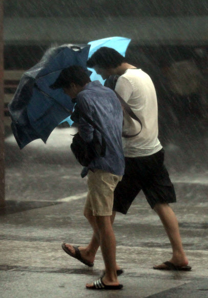 6일 오후 국지성 폭우가 내리고 있는 광화문 거리를 시민들이 걸어가고 있다. 연합뉴스