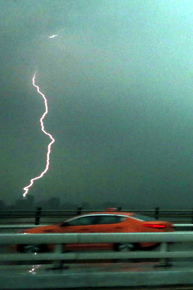 서울 지역에 천둥, 번개를 동반한 폭우가 쏟아진 6일 오후 서울 영등포구 여의동 서강대교 남단 부근에 차량들이 오가는 가운데 번개가 치고 있다. 연합뉴스