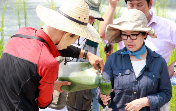 이명박 전 대통령 마스크를 쓴 시민단체 회원이 이미경 국회의원에게 지난주 대구취수장에서 채취한 녹조때문에 짙은 녹색을 띠고 있는 낙동강물을 와인잔에 따라주는 퍼포먼스를 진행하고  있다.  연합뉴스