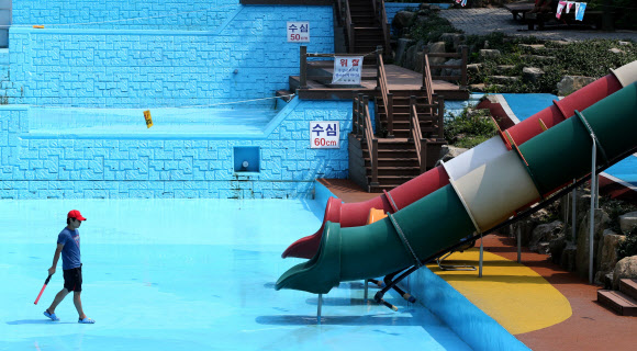 30도를 웃도는 폭염이 연일 기승을 부리는 가운데 8일 전남 나주 금성산 생태 물놀이장에 물이 말라 안전요원이 수영장 바닥을 걷고 있다. 지난달 15일 개방한 생태 물놀이장은 해발 451m의 금성산 정상에서 내려온 물을 끌어 사용하지만 가뭄과 무더위로 지난 6일 임시 휴장에 들어갔다. 연합뉴스
