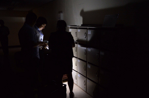전력수급경보 ‘준비’단계에 머무르고 있는 12일 삼성동 한국전력거래소 직원 사무실에서 직원들이 형광등을 끈 채 손전등으로 우편물을 찾는 업무를 보고 있다. 이언탁 utl@seoul.co.kr