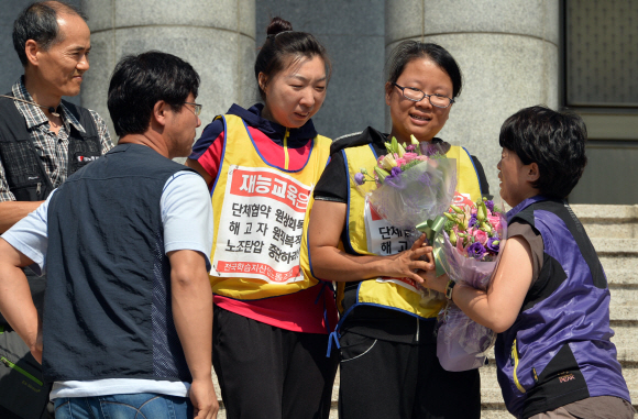 26일 오후 서울 재능교육 앞 혜화성당에서 농성중이던 노동자가 농성을 풀고 내려와 관계자에게 꽃다발을 전달받고 있다. 박지환 popocar@seoul.co.kr