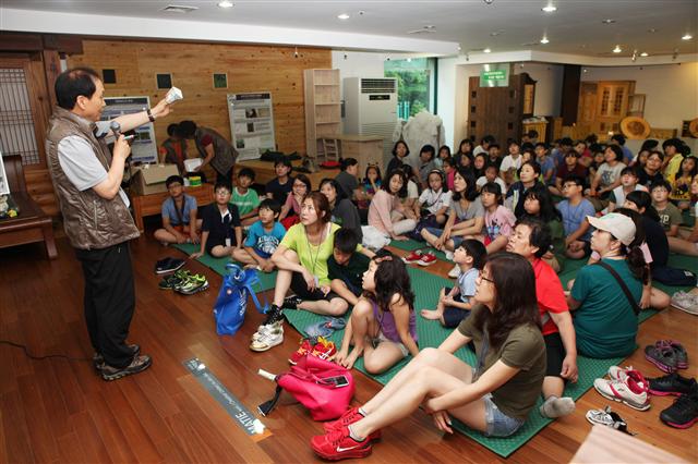 서울 홍릉숲에서 열리는 기후변화와 산림 아카데미에 참가한 초등학생과 학부모 등이 산림의 역할 및 중요성에 대한 설명을 듣고 있다.