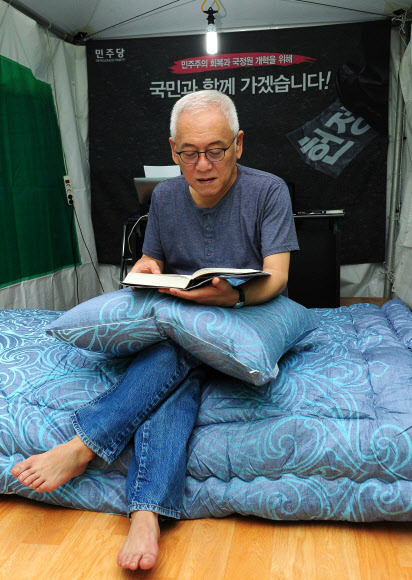 서울광장 ‘노숙투쟁 ‘에 들어간 김한길 민주당 대표가 27일 저녁 서울 중구 태평로 서울시청 앞 광장 국민운동본부 천막 옆에 마련한 별도 천막에서 침대 위에 앉아 책을 읽고 있다.  << 민주당 제공 >>