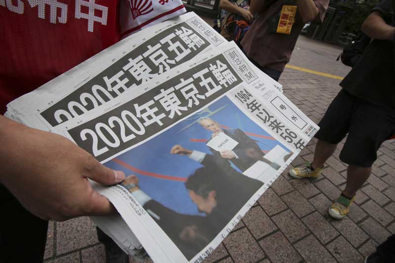 일본 노점상이 8일 도쿄가 2020년 하계올림픽 개최지로 선정됐다는 소식이 실린 신문 호외를 나눠주고 있다. 현지 신문들이 이날 1964년 도쿄올림픽에 이어 56년 만에 도쿄가 올림픽 개최지로 선정됐다고 보도했다. 됴쿄=AP/뉴시스