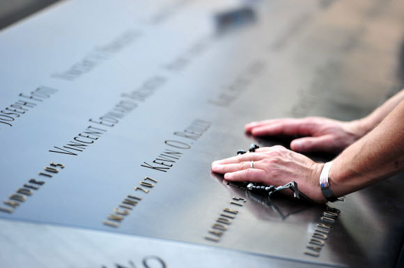 11일(현지시간) 미국 911테러 추모공원에서 희생자의 이름을 새긴 메모리얼을 만지며 슬픔에 잠겨 있다. AP 연합뉴스