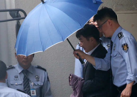 내란 음모 등의 혐의로 구속 기소된 이석기(가운데) 통합진보당 의원이 14일 경기 수원시 수원지방법원에서 열린 첫 공판준비기일에 출석한 뒤 우산으로 얼굴을 가린 채 지법을 빠져나오고 있다. 박지환 기자 popocar@seoul.co.kr