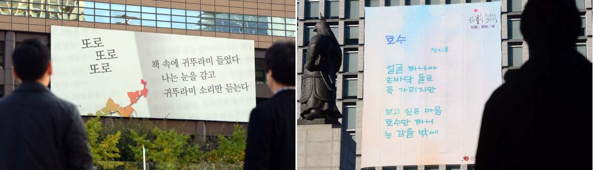 30일 서울 광화문 이순신 동상을 사이에 두고 마주 보고 있는 교보생명(왼쪽)과 현대해상 건물 외벽에 걸린 시를 지나가는 시민들이 감상하고 있다. 