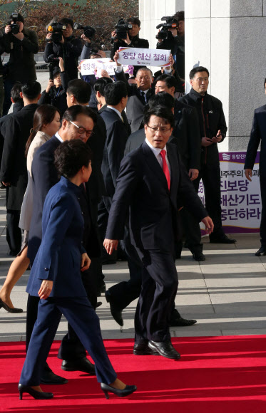 박근혜 대통령이 국회 시정연설을 위해 18일 오전 국회의사당 본관으로 입장하고 있다. 박 대통령 뒤쪽으로 국회 현관 앞에서 농성중인 통합진보당 의원들이 ’정당해산철회’ 라고 적힌 손 현수막을 들고 시위하고 있다. 연합뉴스