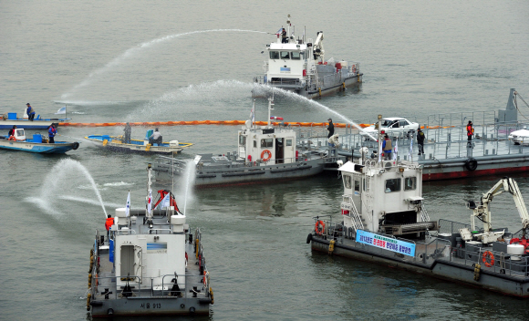 22일 오전 여의도 한강에서 열린 겨울철 수난사고 대비 유관기관 합동 구조훈련에서 서울시 소방재난본부 소속 119특수구조단 대원들을 비롯한 훈련 참가자들이 마포대교 상판이 붕괴되면서 다리 밑을 통과하던 유람선에서 화재가 난 상황을 가정해 기름 제거 및 확산 방지 활동을 하고 있다. 박지환 popocar@seoul.co.kr