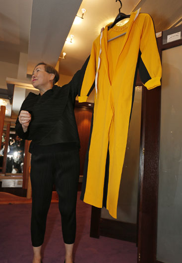 스핑크 경매사 부사장 애나 리 씨가 2일 홍콩에서 열린 기자회견에서 배우 브루스 리(이소룡)가 썼던 쌍절곤·노란색 운동복과 함께 포즈를 취하고 있다.  AP/뉴시스