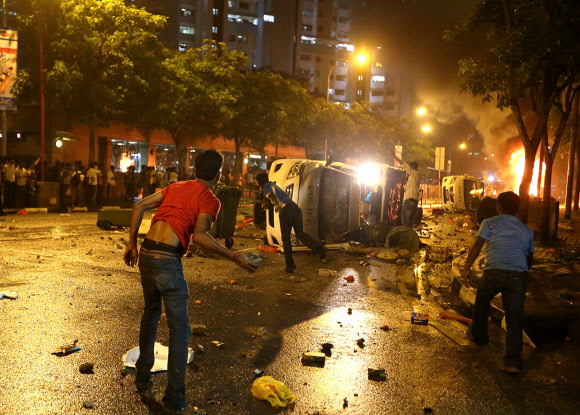8일 오후 싱가포르 시내 외국인 거주지역인 ‘리틀 인디아’에서 인도계 노동자가 버스에 치여 숨진 사건에 항의하는 외국인 노동자들이 경찰차에 불을 지르고 출동한 경찰을 향해 돌을 던지고 있다. 싱가포르 AFP 연합뉴스
