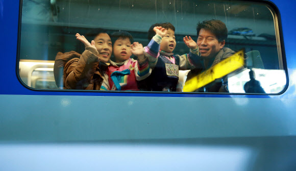 설 연휴가 시작된 29일 오전 서울역에서 귀성열차에 오른 한 가족이 손을 흔들고 있다. 연합뉴스