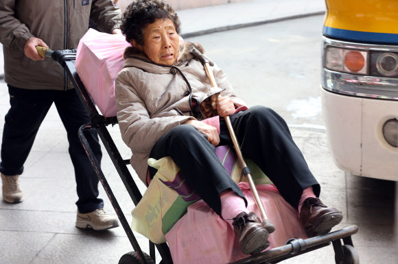 설 연휴를 하루 앞두고 본격적인 귀성이 시작된 29일 서울 강남고속버스터미널에서 한 시민이 손수레에 짐과 어르신을 싣고 이동하고 있다.  연합뉴스