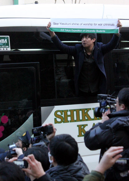 강제로 버스에 태워진 원정대의 한 남성이 야스쿠니 신사 참배를 반대하는 내용의 천을 펼쳐 보이고 있다.  연합뉴스