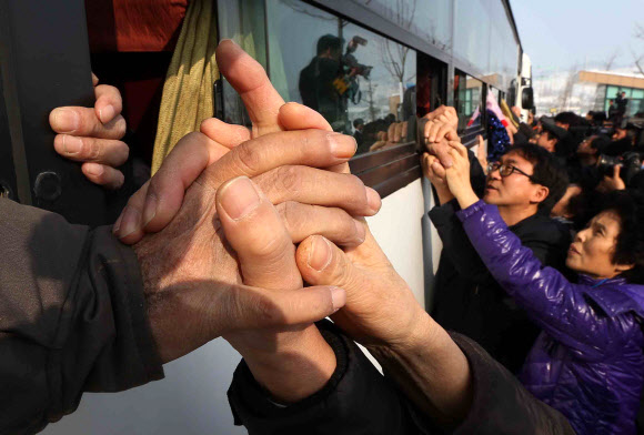 이산가족 상봉행사 2차 마지막날인 25일 오전 금강산면회소에서 열린 작별상봉을 마친 남측 가족들이 버스에 탑승한 북측 가족들과 헤어지며 손을 부여잡고 있다.연합뉴스