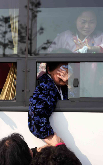 이산가족 상봉행사 2차 마지막날인 25일 오전 금강산면회소에서 열린 작별상봉을 마친 북측 상봉자들이 버스에 탄 채 남측 가족들의 손을 붙잡고 눈물을 흘리고 있다. 연합뉴스