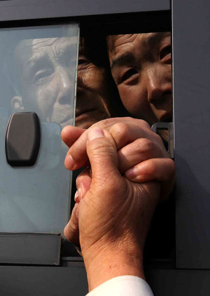 이산가족 상봉행사 2차 마지막날인 25일 오전 금강산면회소에서 열린 작별상봉을 마친 북측 상봉자들이 버스에 탄 채 남측 가족들의 손을 붙잡고 있다. 연합뉴스