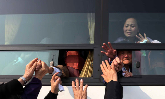 이산가족 상봉행사 2차 마지막날인 25일 오전 금강산면회소에서 열린 작별상봉을 마친 남측 상봉자들이 버스에 북측 가족들과 헤어지며 손을 붙잡고 있다.연합뉴스