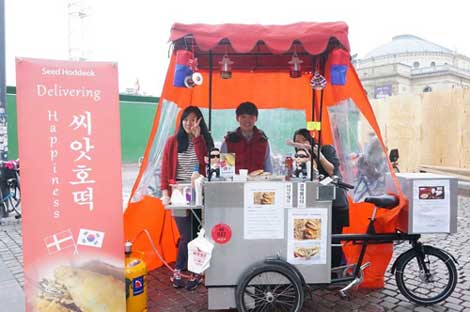 ‘행복 배달 포차’의 김희욱(가운데)씨가 덴마크 코펜하겐의 중심가에서 씨앗호떡을 만들어 팔고 있다.
