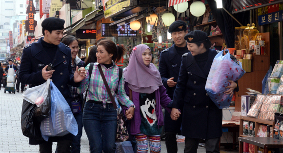 서울 남대문시장에서 관광경찰대원들이 쇼핑을 나선 브루나이 관광객들의 짐을 들어 주며 관광 안내를 하고 있다. 관광경찰은 지난해 외국인 관광객들이 각종 불법행위와 불편사항을 겪는 것을 줄이고자 출범했다.