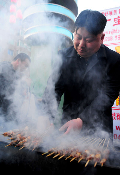 22일(현지시간) 중국의 심양에서 북한 김정은 국방위 제1위원장과 닯은 거리 음식 상인이 꼬치를 굽고 있다.  ⓒ AFPBBNews=News1