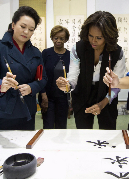21일 베이징사범대학 제2부속중학교를 방문한 미셸여사와 펑리위안 여사가 서예 실습도 동참했다. 미셸은 학생들의 도움을 받아 ‘영’(永)자를 붓글씨로 직접 써서 펑 여사에게 선물했다.ⓒ AFPBBNews=News1