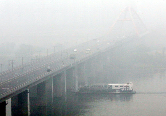 서울지역에 올해 첫 미세먼지 주의보가 발령된 16일 오후 안개와 미세먼지에 가려진 서강대교 아래로 배가 지나고 있다. 연합뉴스