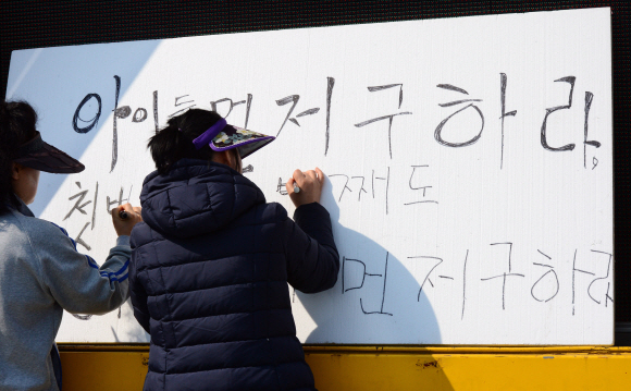 세월호 실종자 가족들이 24일 전남 진도군 팽목항에서 ‘아이들을 먼저 구하라’는 절실한 호소를 널빤지에 적고 있다. 진도 박지환 기자 popocar@seoul.co.kr