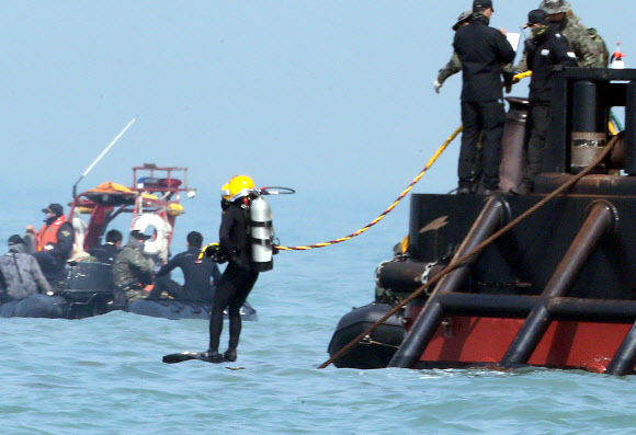 공기공급호스를 문 민간잠수사(머구리)가 24일 오전 전남 진도군 병풍도 세월호 침몰 해상을 수색하기 위해 바다로 뛰어들고 있다. 머구리들은 길이를 연장한 공기호스를 착용해 깊은 곳에서 들어가 수색할 수 있다.  연합뉴스